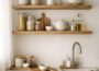 Calm modern kitchen with wooden open shelves, neutral ceramics, glass jars, and soft natural Scandinavian styling.